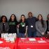 Students and faculty standing behind table