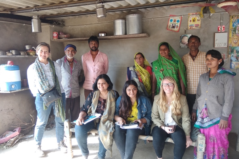 Ten persons posing for a photo. Six stand in the back and four sit in front.