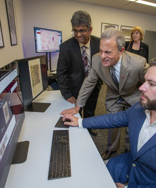 University leadership looking at computer screen in Center for Digital Humanities