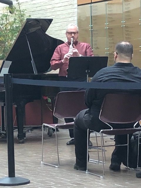 Man playing clarinet in front of piano