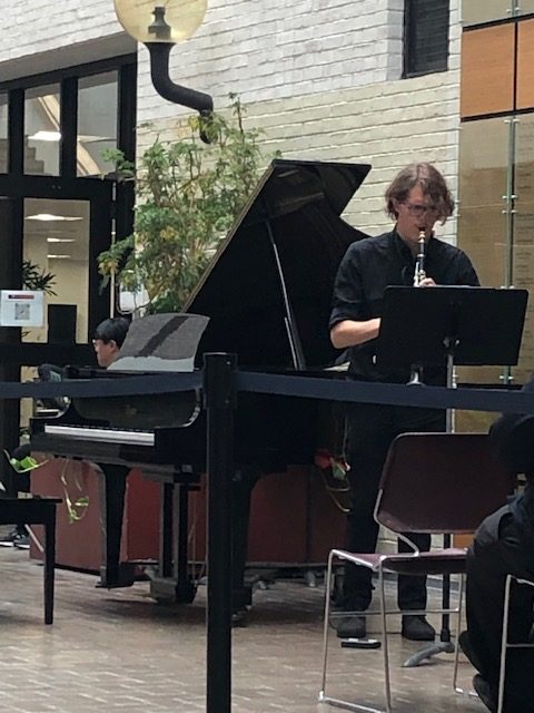 Man playing clarinet in Galleria next to piano