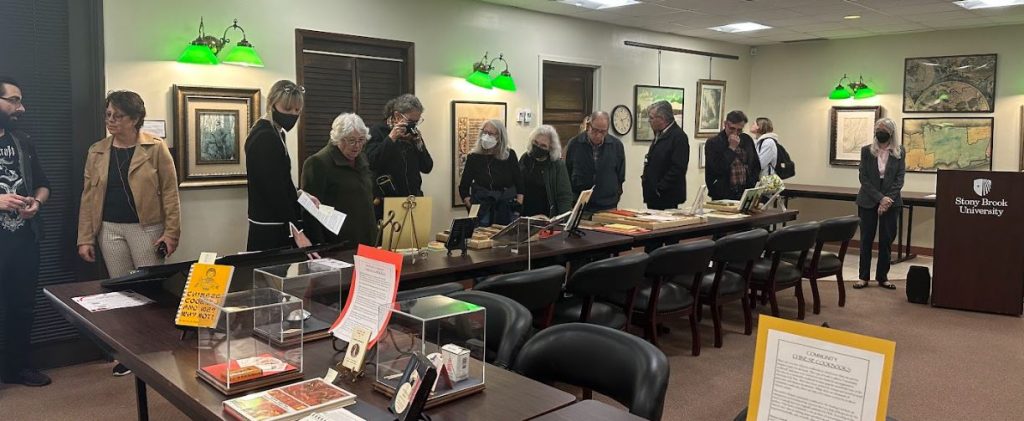 Photograph of people looking at books and artifacts about Chinese food and culture. Taken at the Art Crawl in Special Collections, Melville Library, Stony Brook University on April 26, 2023.