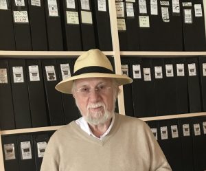 Dan Rattiner posing in front of the Dan’s Papers archive donated to Stony Brook University Libraries, April 2023. Photograph courtesy of Dan's Papers.