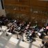 AI: Overhead view of courtyard with brick wall left, glass window right, brick floor, people around table with laptop (AI-generated alt-text)