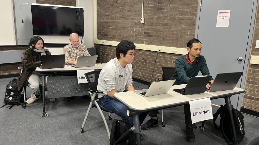 Two people sitting per table, looking at their computers.