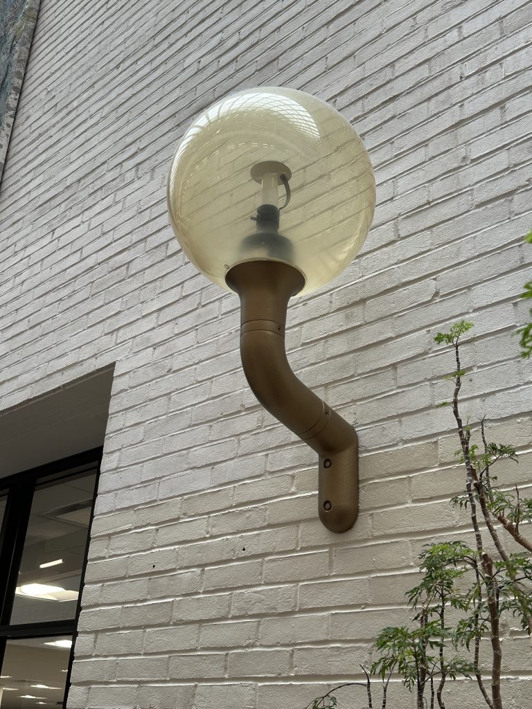 A wall mounted light fixture with a faux-brass finish.