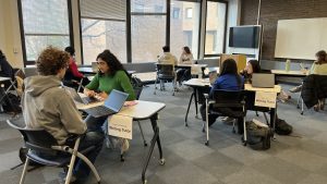 5 pairs of people sitting at 5 tables working over laptops