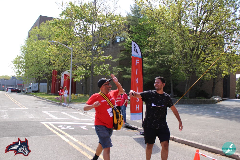 Two runners crossing finish line, one giving highfive.