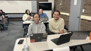 Shows smiling students and librarians sitting at desks with their laptops.