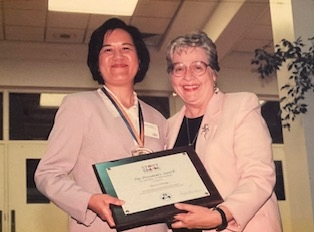 Female librarian holding an award next to another woman. 