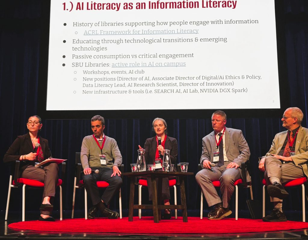 Five spearkers seated on stage. 