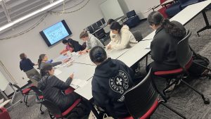 Students and faculty sitting around a table drawing