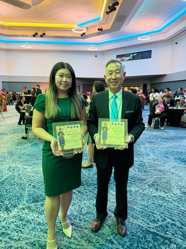 Sunny Chung and Michael Huang holding their JCLC awards in a conference hall